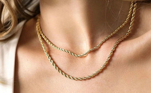 Close-up of a model wearing two layered, classic twisted gold rope chain necklaces for women.