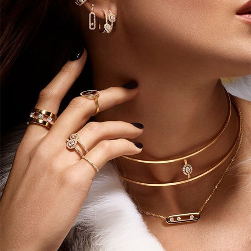 Model wears layered gold choker necklaces, modern diamond rings, and matching gold earrings. Fine jewelry collection.